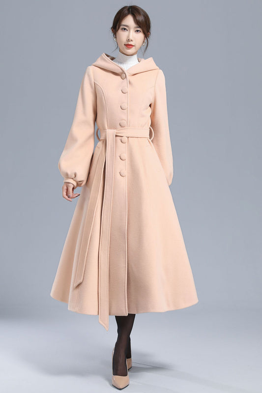 Woman wearing handmade light beige hooded wool coat with lantern sleeves and belt