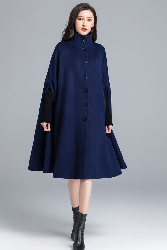 Woman wearing a navy blue coat with black sleeves on a gray background