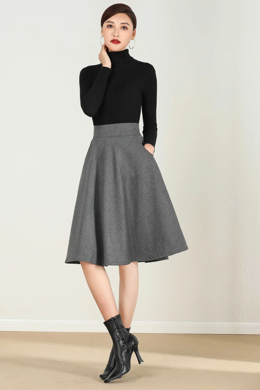 A woman wearing a short A-line winter wool skirt in a gray color, paired with a black turtleneck top and black boots.