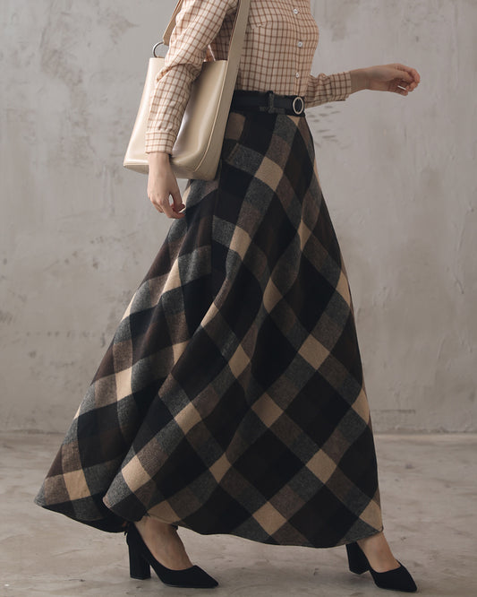 A person wearing a plaid wool maxi skirt with a classic high-waisted A-line cut, paired with a checkered long-sleeve top and black shoes, carrying a beige handbag.