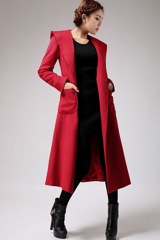 A woman modeling a long red winter wool coat with button front and tie belt waist, paired with a black top and black boots.