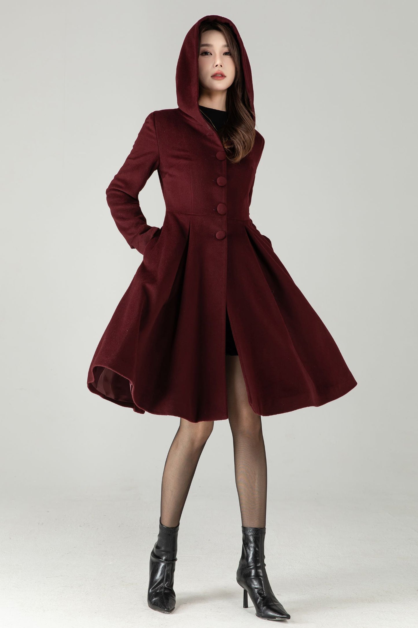 Woman wearing a burgundy hooded coat on a white background