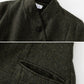 Dark green herringbone patterned coat with buttons on a white background