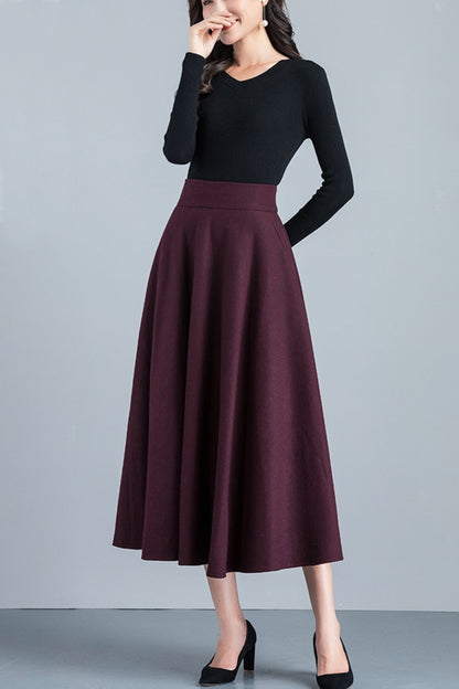 Woman wearing a black top and burgundy skirt on a gray background