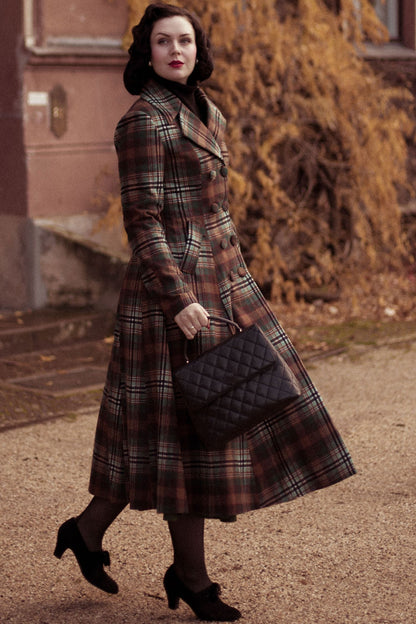 A woman wearing a vintage inspired winter plaid long wool coat with double breasted design, long sleeves, and a notch lapel, paired with a black handbag.