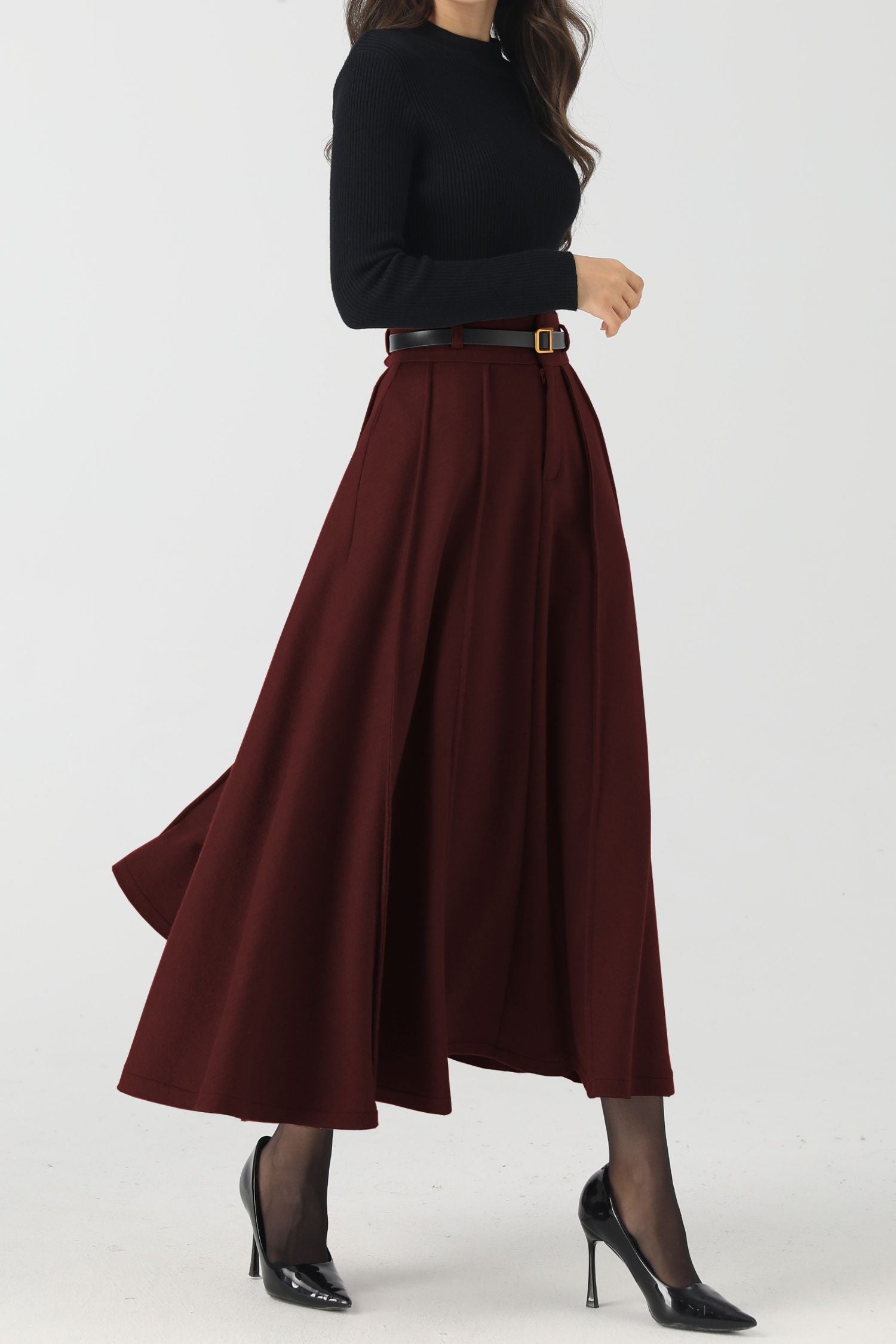 Person wearing a black top and burgundy skirt on a white background