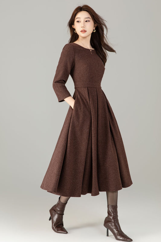 Woman wearing a brown dress with long sleeves and a full skirt on a plain background