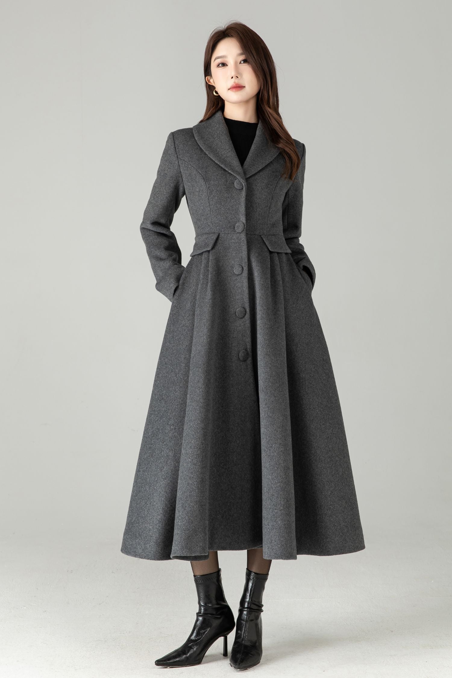 Woman wearing a long gray coat on a plain background