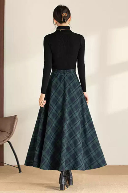 Person wearing a black turtleneck and plaid skirt in a minimal indoor setting