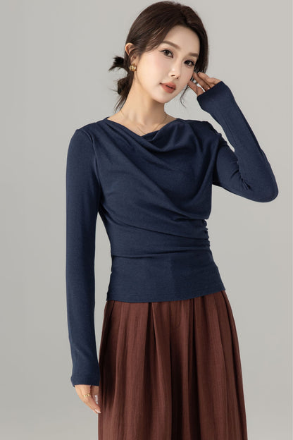A woman wearing a navy blue long sleeve knit top with a flared neck and no visible pockets.