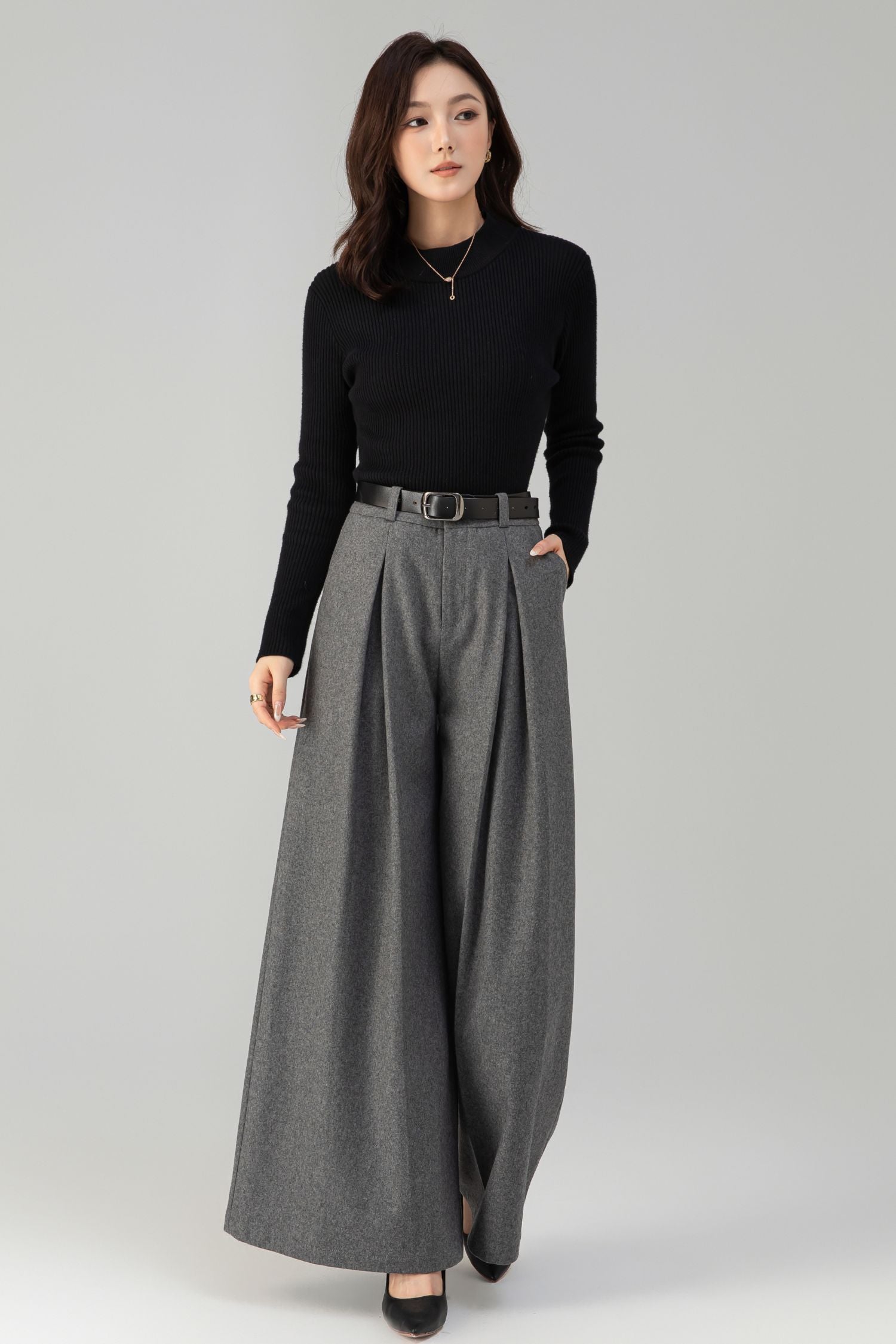 Woman wearing a black top and gray wide-leg pants on a white background