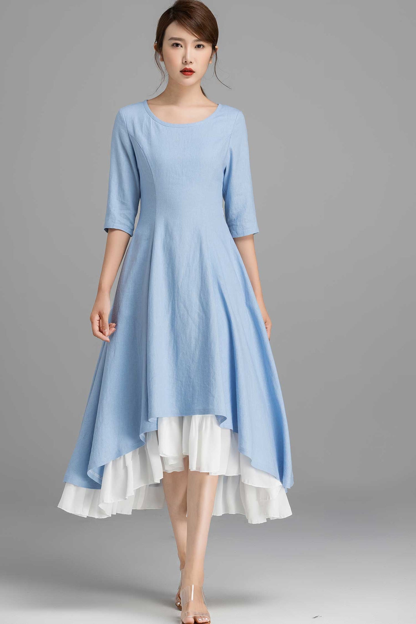 Woman wearing a light blue dress with a white hem on a gray background