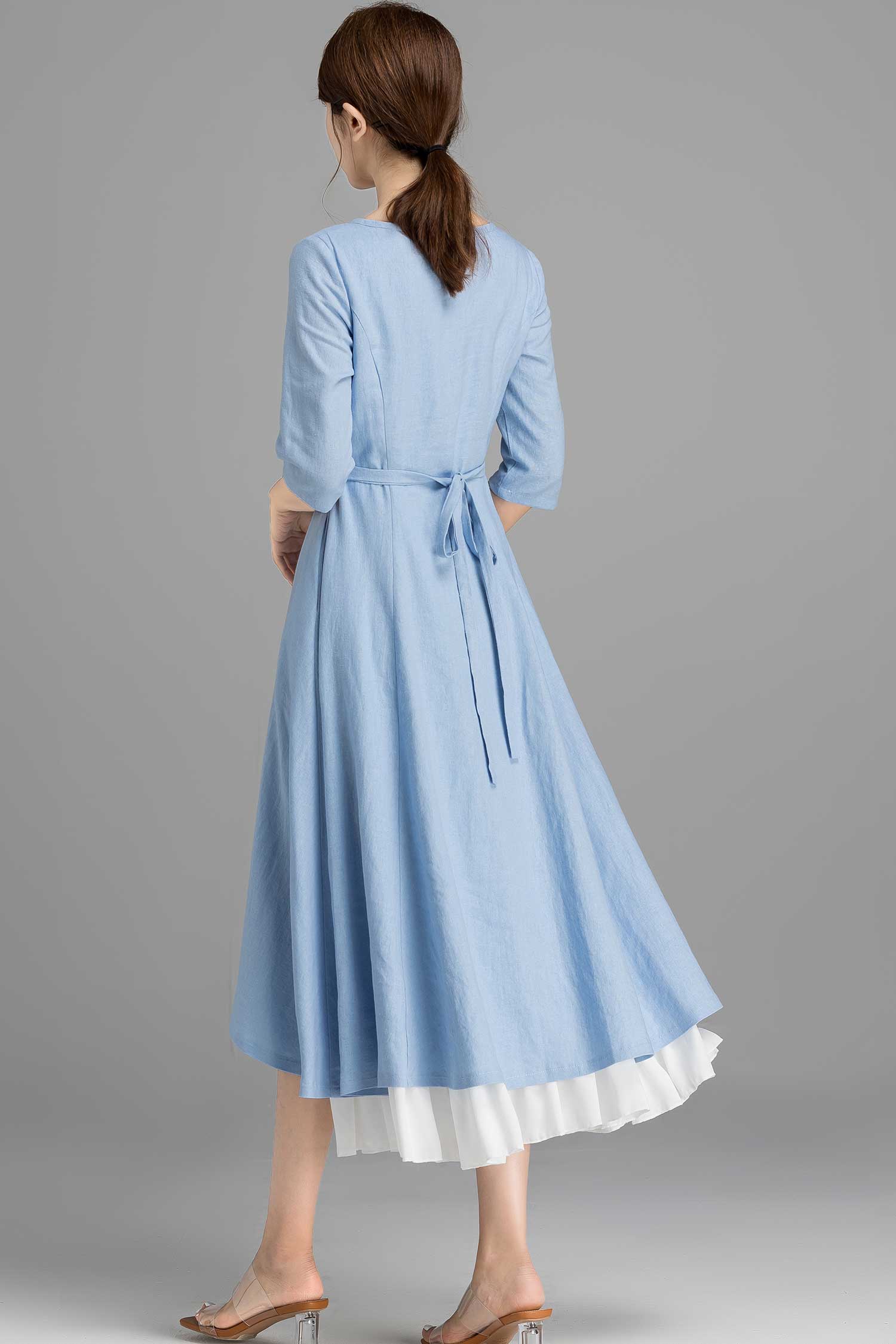 Woman wearing a light blue dress with a white hem on a gray background