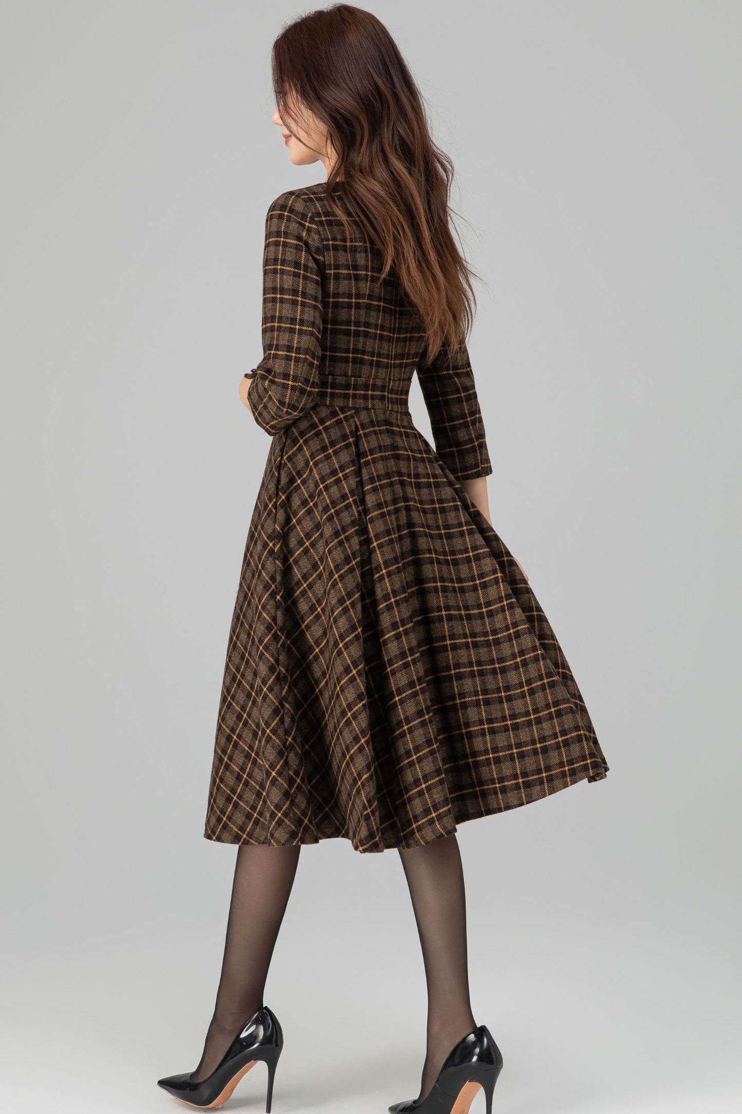 Woman wearing a brown plaid dress on a gray background
