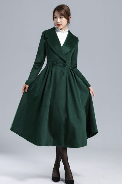 A model wearing a dark green fit and flare wool coat with a white blouse and black skirt.