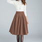 Woman wearing a wool skater skirt with side pockets and a back zipper in brown