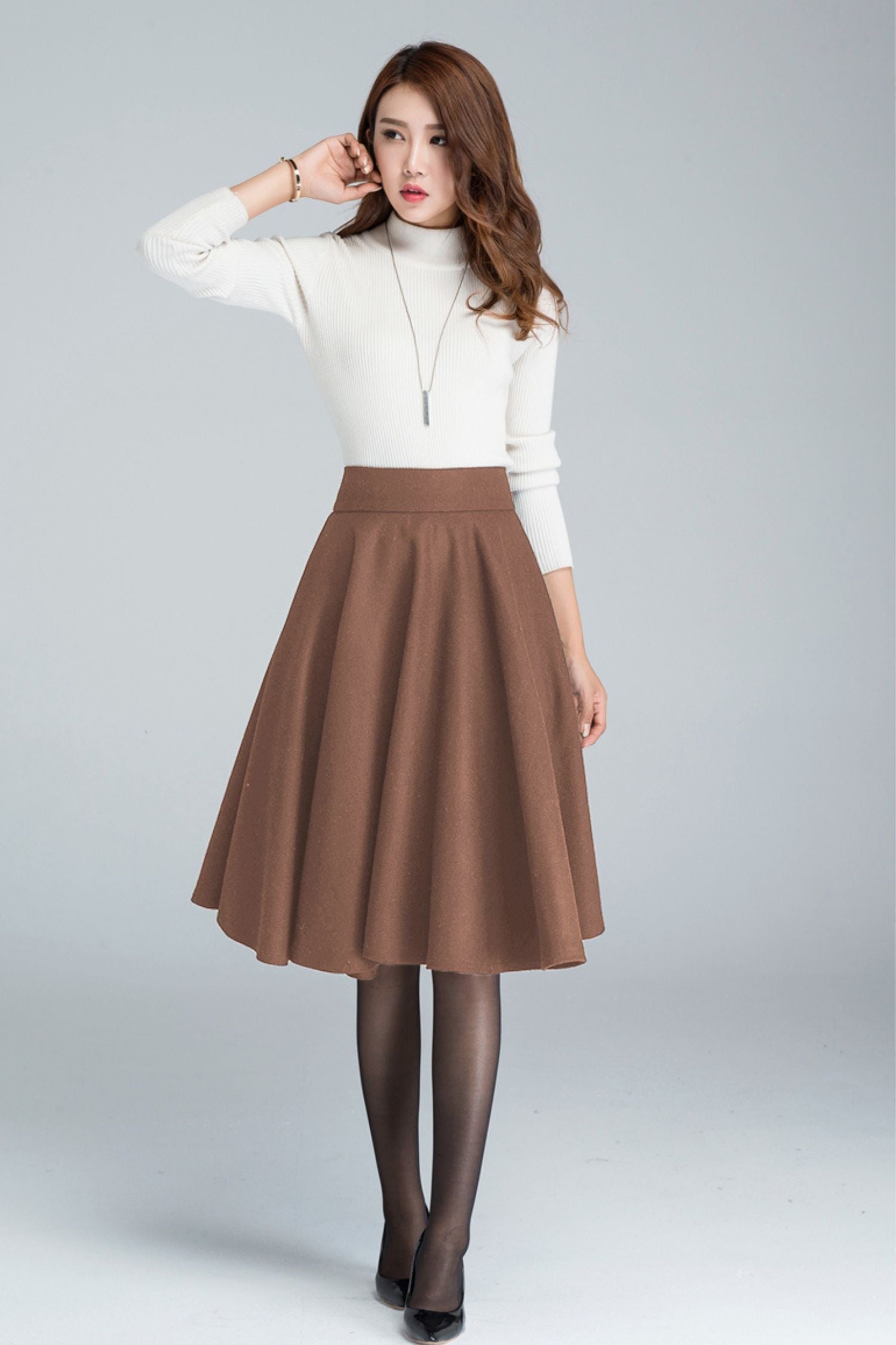 Woman wearing a wool skater skirt with side pockets and a back zipper in brown