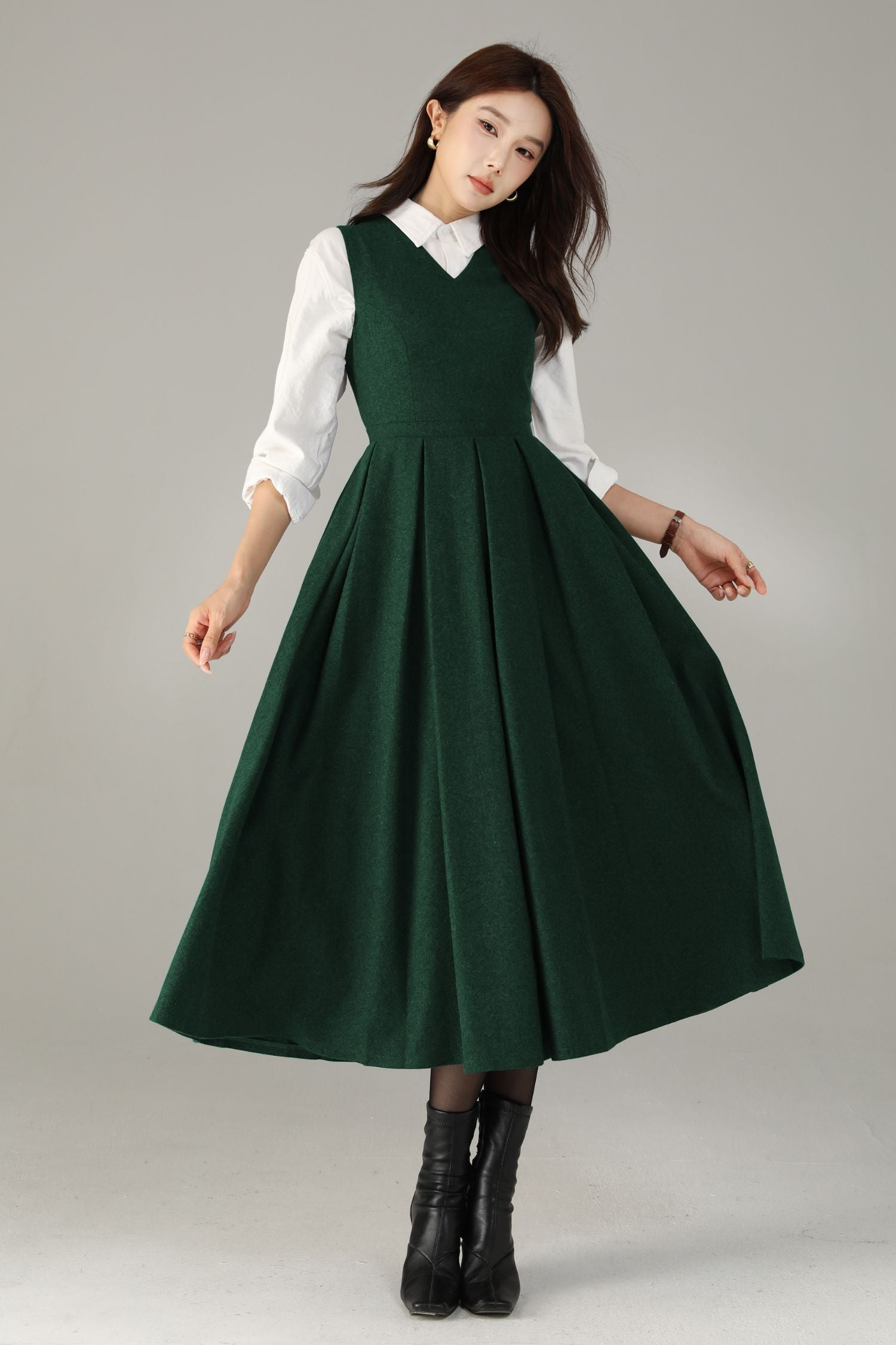 Woman wearing a green dress over a white shirt on a gray background