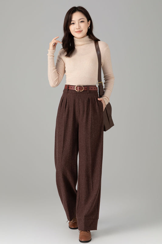 Woman wearing a beige turtleneck and brown wide-leg pants with suspenders on a gray background