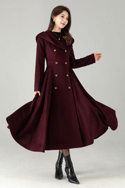 Woman wearing a burgundy coat with gold buttons on a gray background
