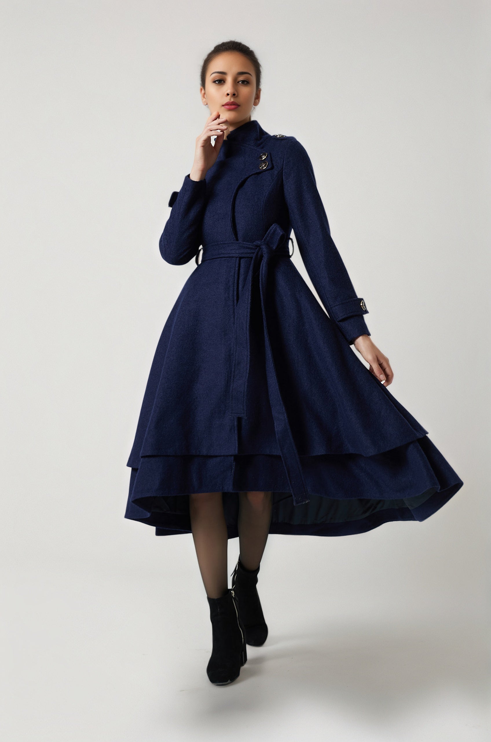 Woman wearing a navy blue coat with a white background