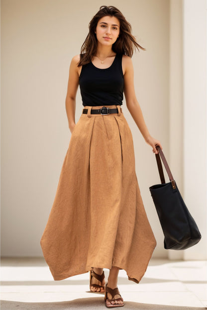 A woman wearing a high-waisted, beige maxi casual skirt with a black belt, black sandals, and carrying a black tote bag.