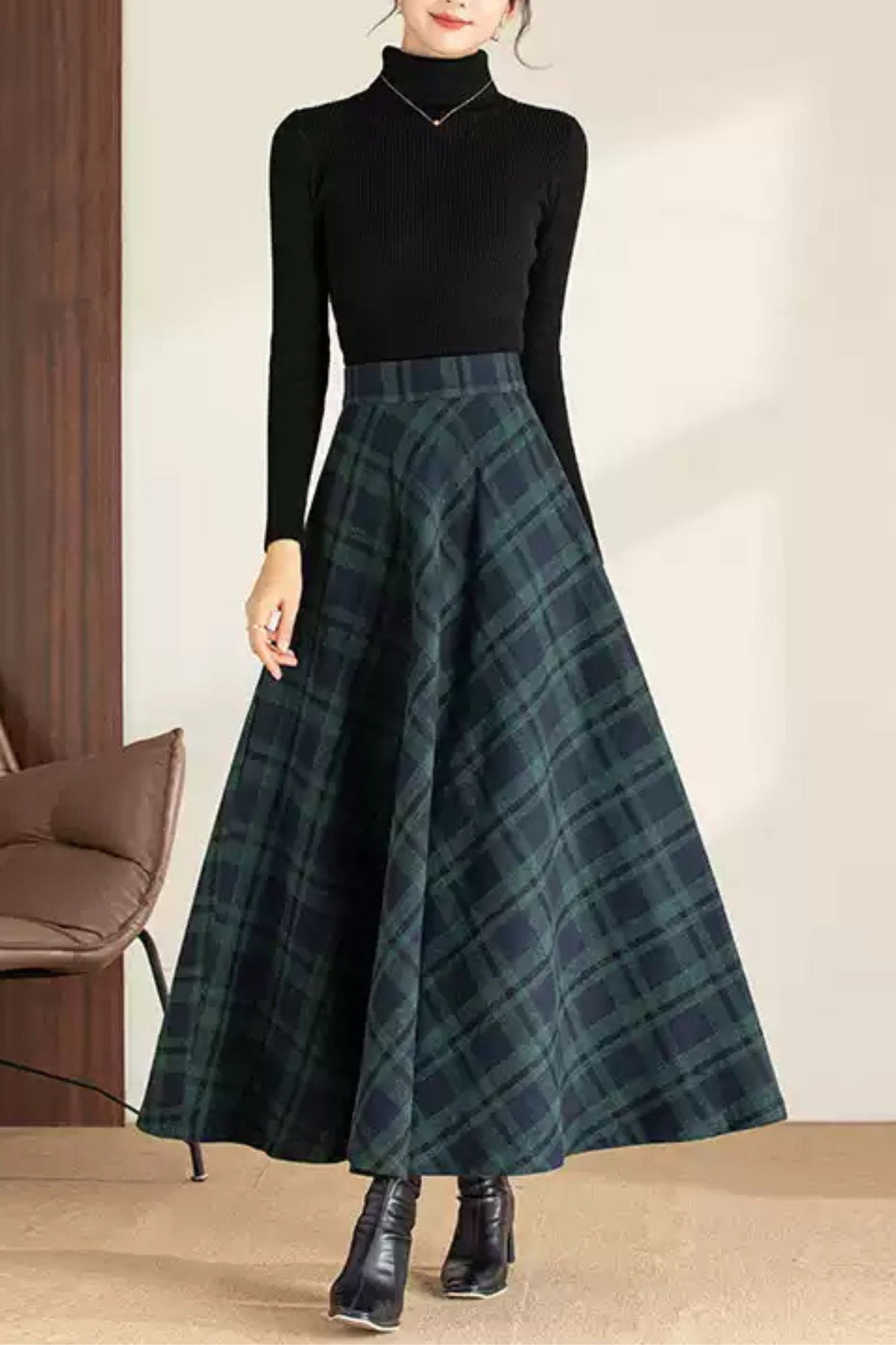 Person wearing a black turtleneck and green plaid skirt indoors.