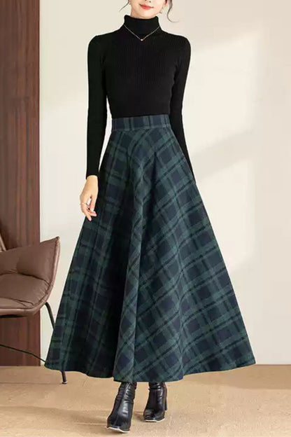Person wearing a black turtleneck and green plaid skirt indoors.