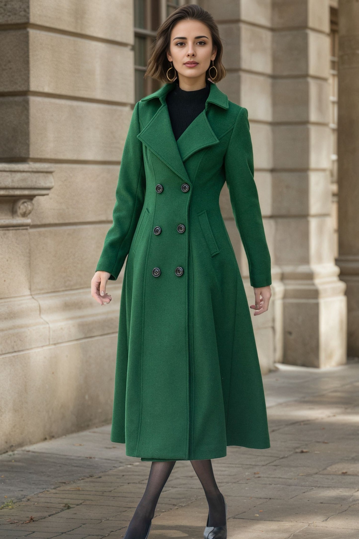 Woman wearing a green coat standing in front of a stone building.