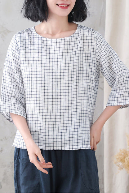 A woman smiling, wearing a loose fitting plaid summer linen blouse with a round neckline and 3/4 sleeves.