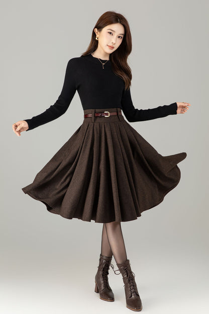 Woman wearing a black top and brown skirt with a belt on a gray background