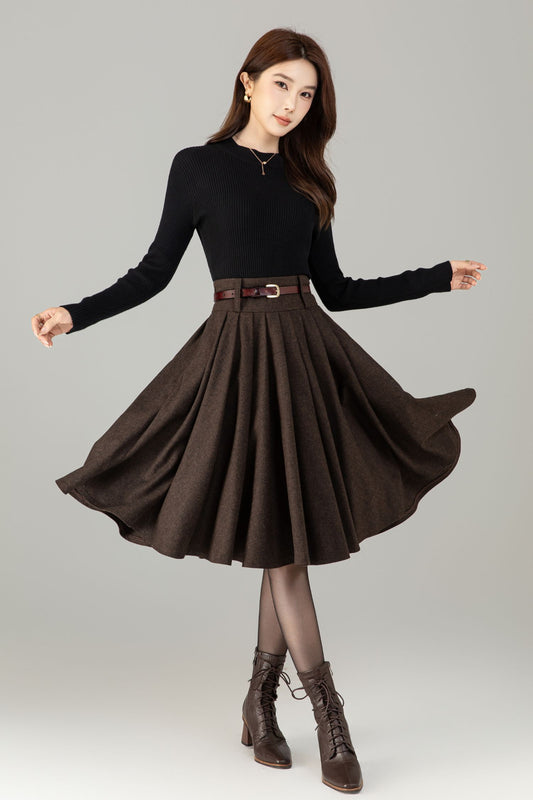 Woman wearing a black top and brown skirt with a belt on a gray background