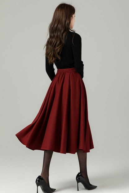 twirling shot of lined burgundy wool midi skirt styled with black heels