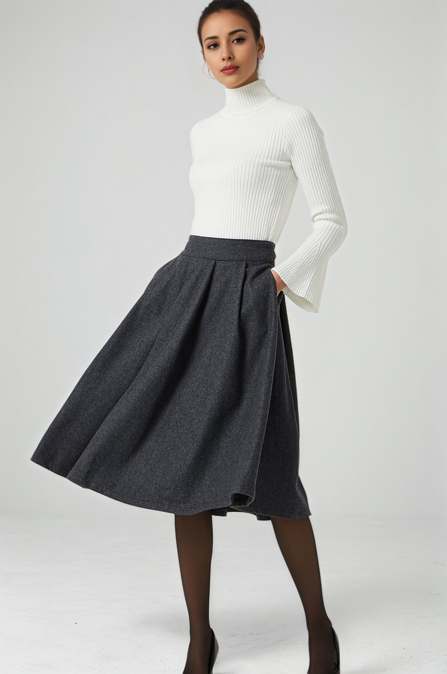 Woman wearing a white turtleneck and gray skirt on a white background