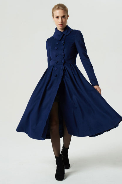 A model wearing a navy blue double-breasted, pleated midi linen skirt with long sleeves and a cinched waist.