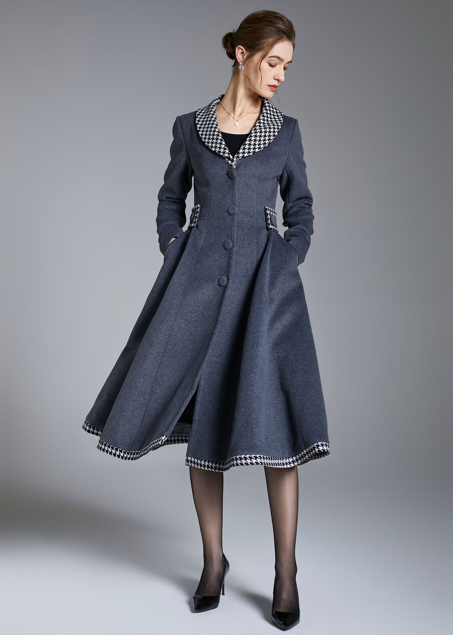 Woman wearing a long blue coat with a checkered collar against a gray background