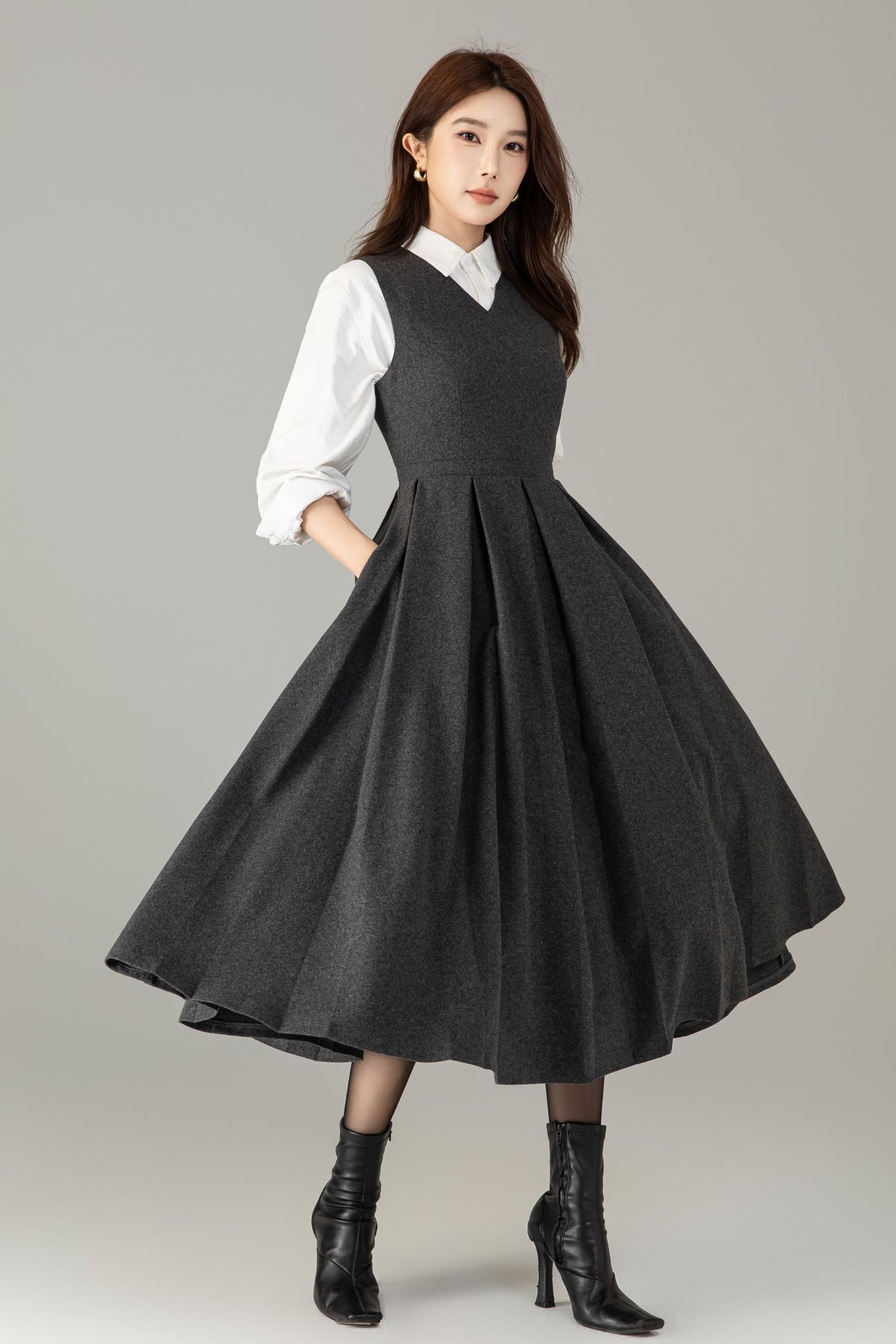 Woman wearing a black dress over a white shirt on a gray background