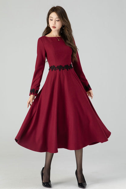 A woman modeling a burgundy midi winter wool dress with lace details, featuring long sleeves and a round neckline.