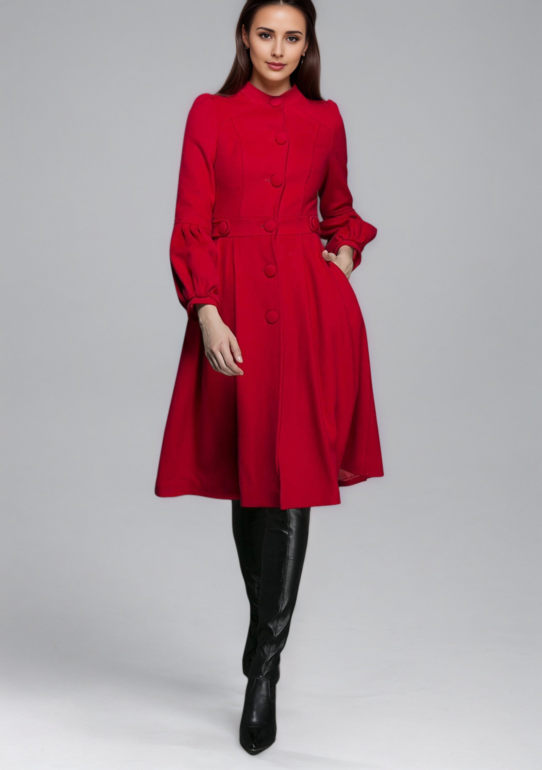 Woman wearing a red dress coat with long sleeves on a gray background