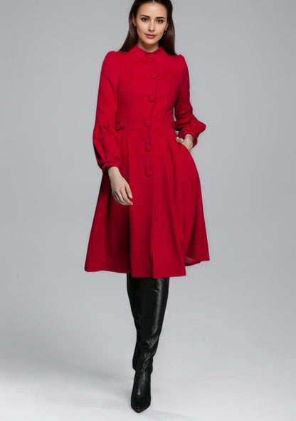 Woman wearing a red dress coat with long sleeves on a gray background