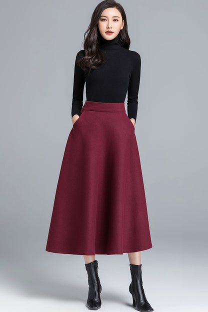 A model wearing a burgundy midi winter wool skirt with a black top and black boots.