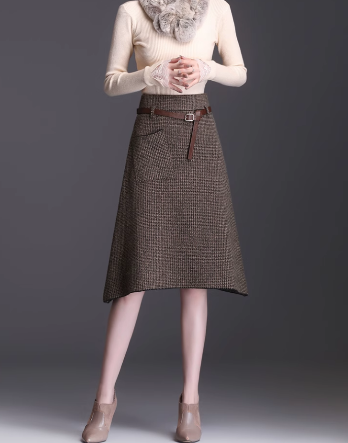 Woman wearing a brown plaid skirt with a belt on a gray background