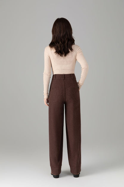 Woman wearing brown high-waisted pants on a gray background