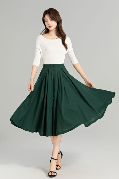 A woman is shown wearing a green, high-waisted linen skirt with a button-down front. She is also wearing a white, solid-colored top and black heels.