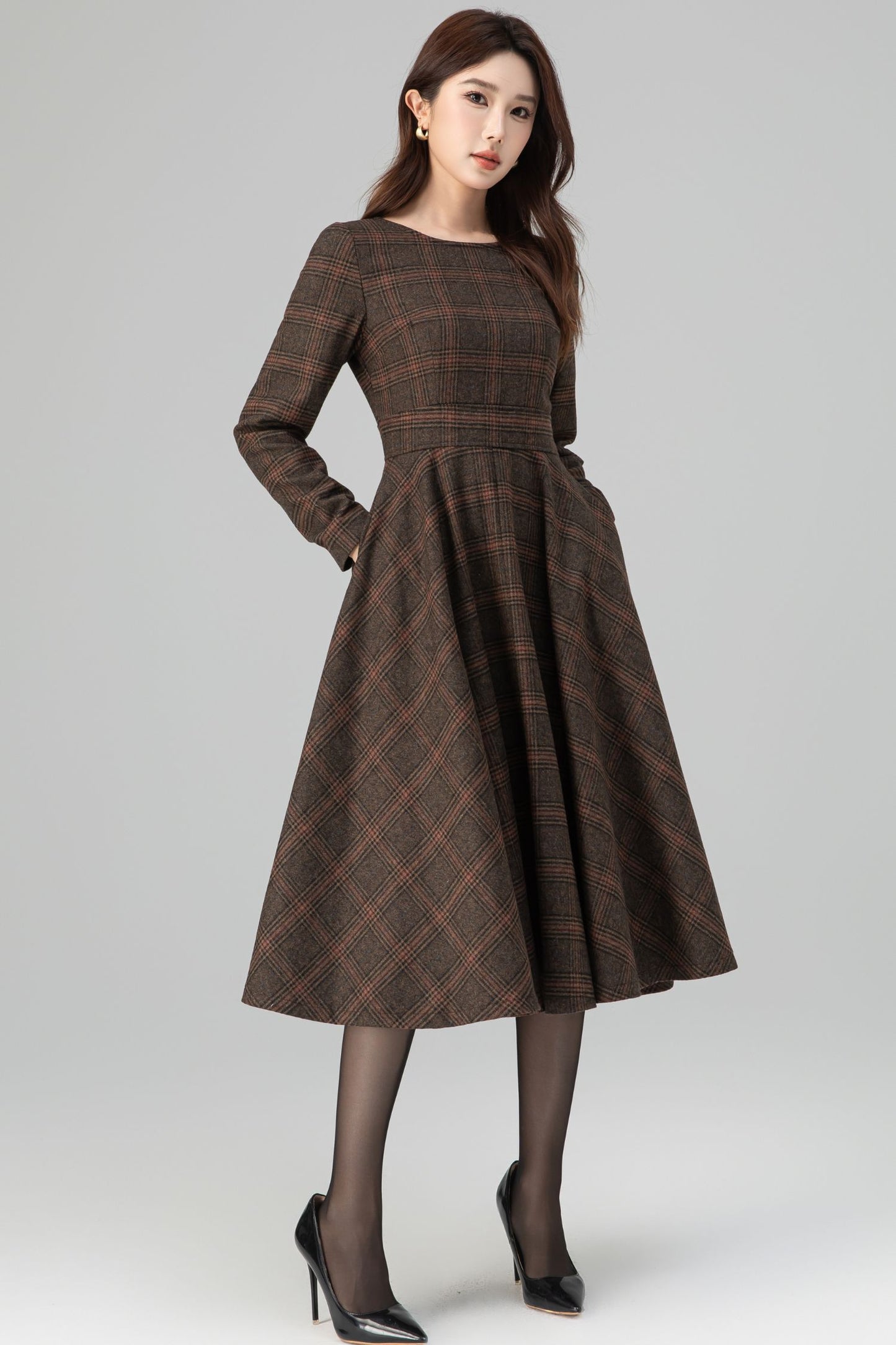 Woman wearing a brown plaid dress on a gray background