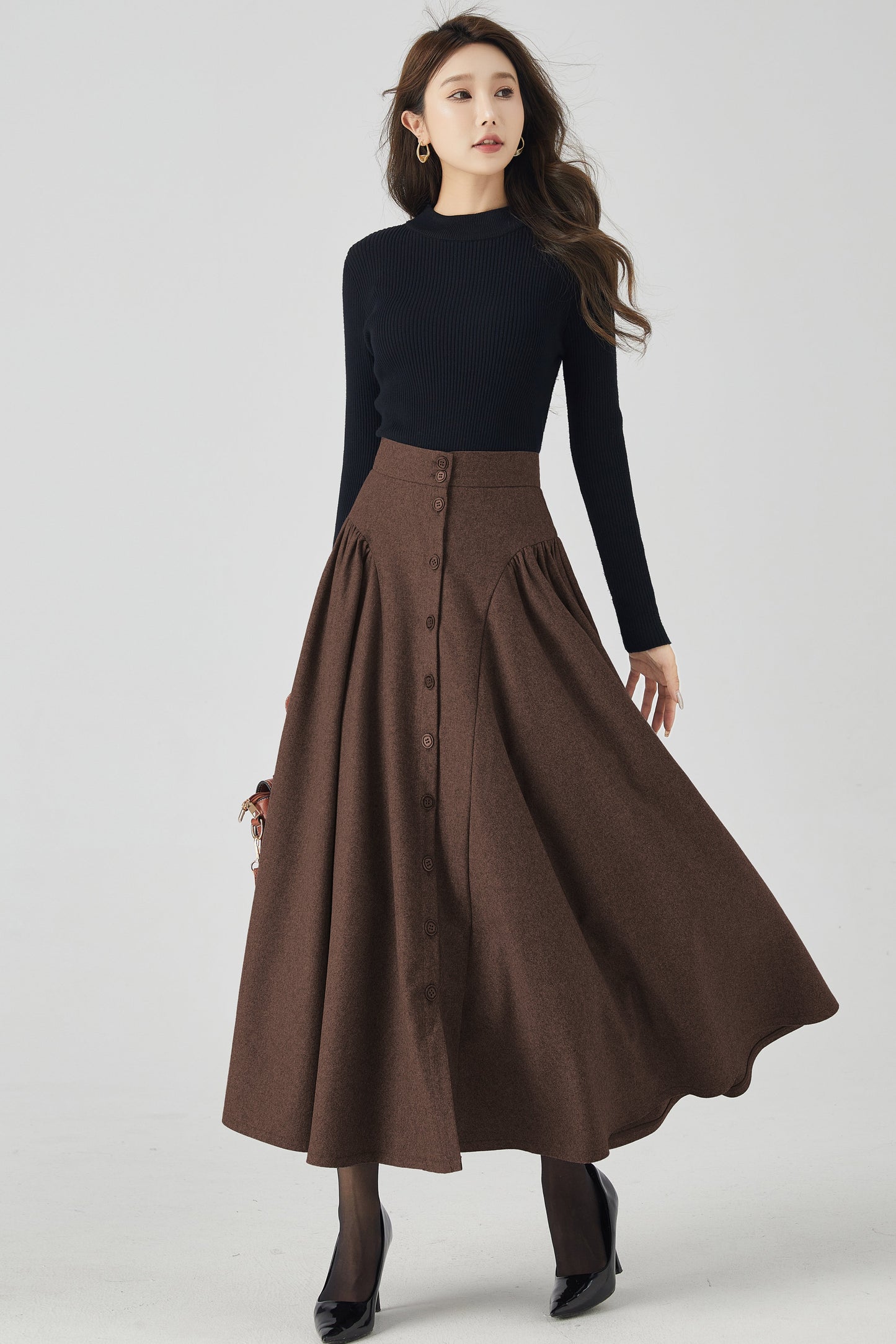 Woman wearing a black top and brown skirt on a white background