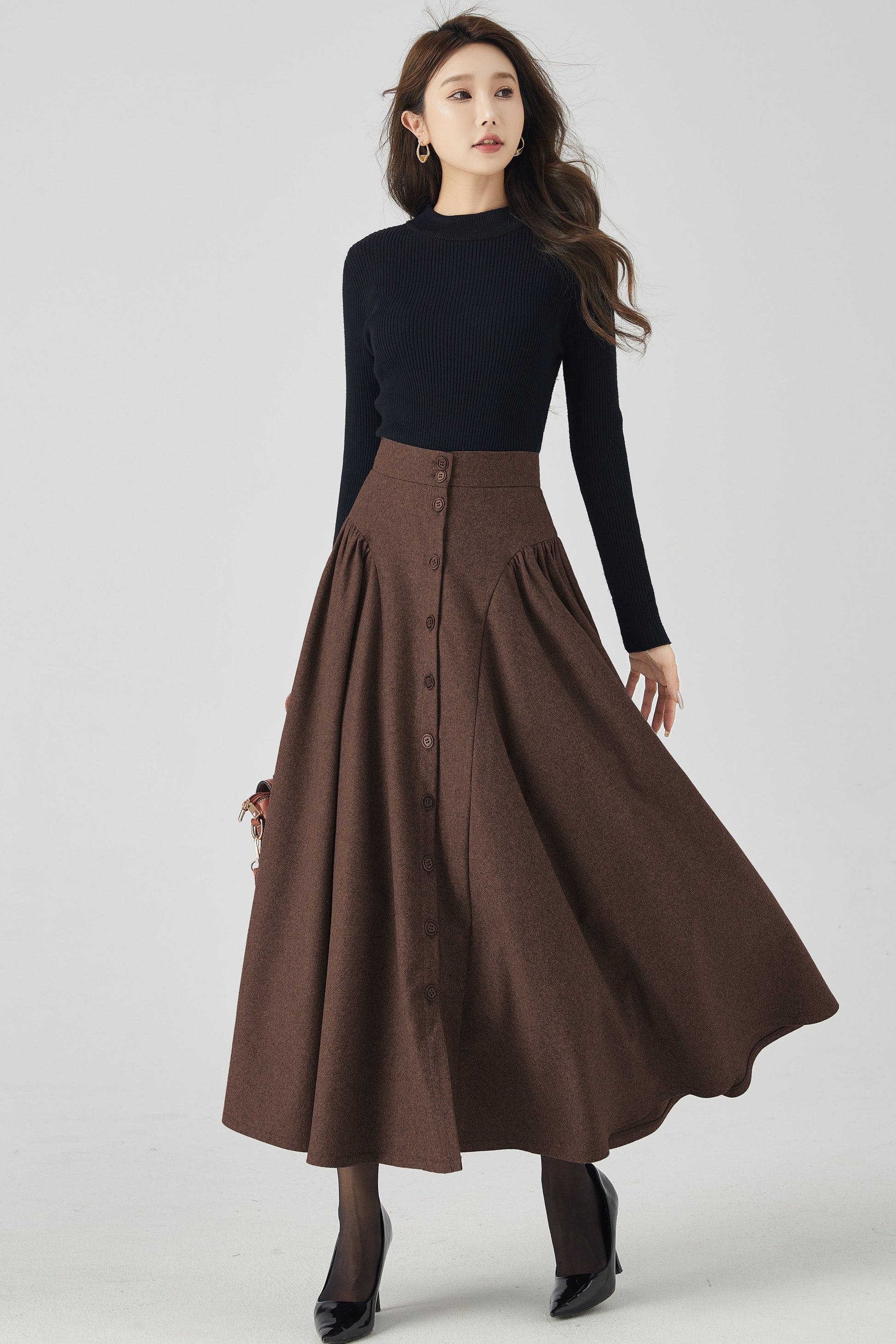 Woman wearing a black top and brown skirt on a white background