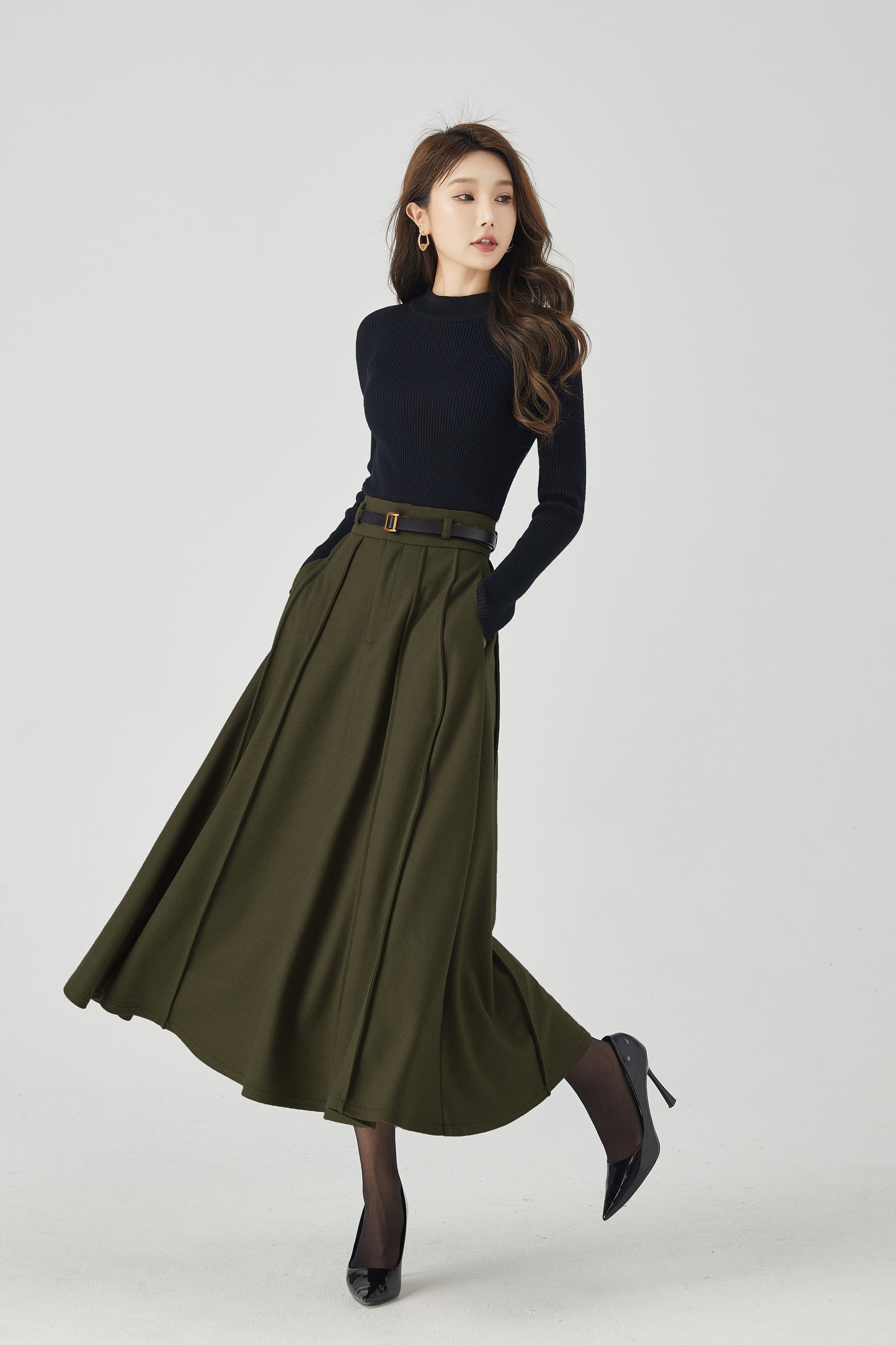 Woman wearing a black top and green skirt on a white background