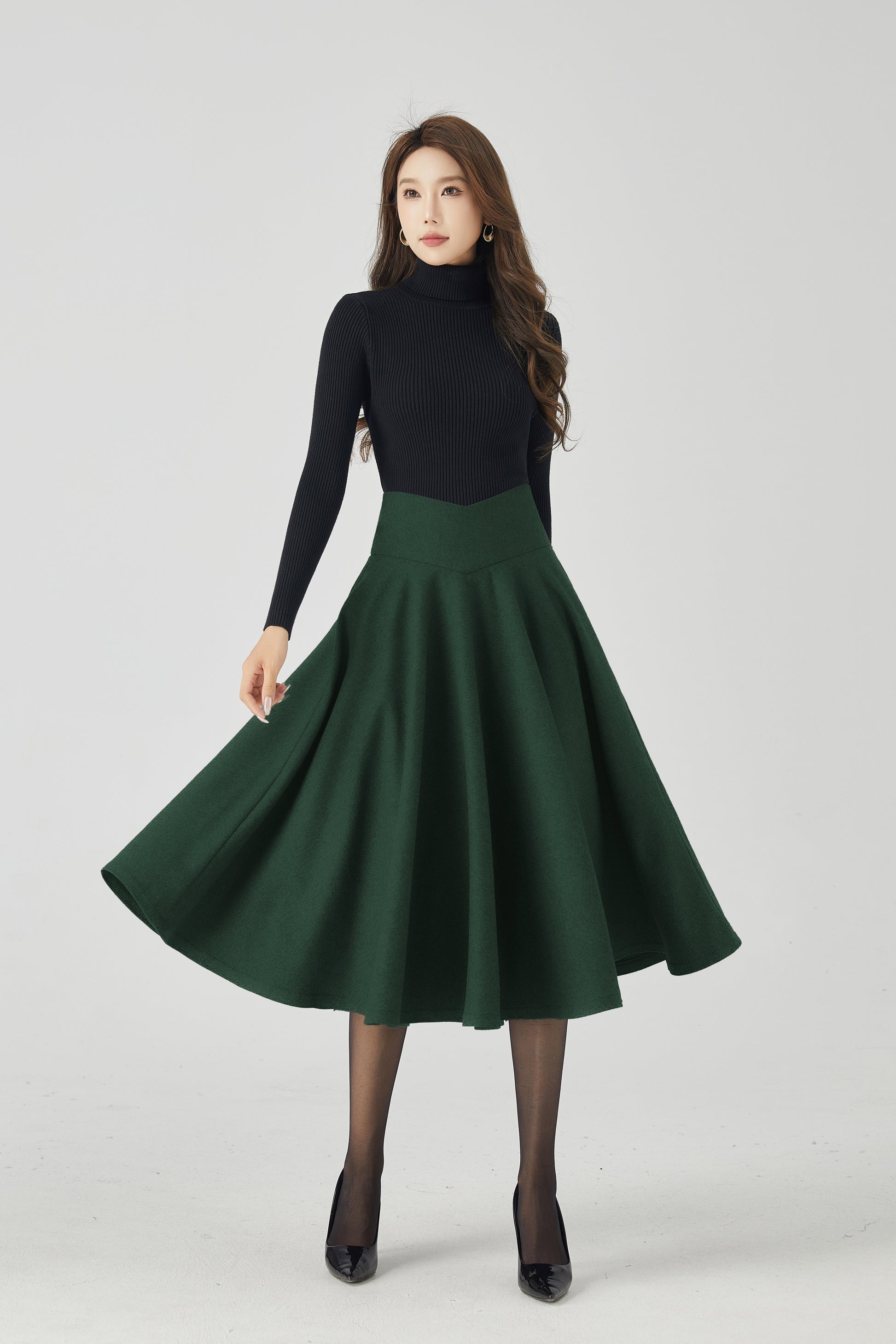 Woman wearing a black turtleneck and green skirt on a white background