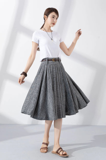 May include: A gray linen skirt with a brown belt and a gold buckle. The skirt is pleated and has a flared silhouette. The skirt is knee-length.